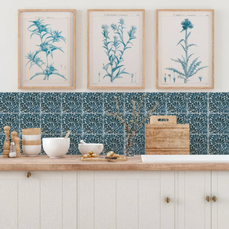 Three framed botanical prints with teal blue illustrations on cream paper in light wood frames for kelmscott emery blue tile