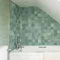 The kelmscott green tile bathroom features a white bathtub with chrome faucet against muted green square tiles