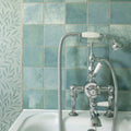 Chrome-finished vintage-style bathtub faucet with white ceramic handles and matching showerhead against kelmscott green tile