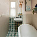 White ceramic pedestal sink with brass plumbing and gold-toned wall light in kelmscott white tile bathroom setting