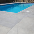 Rectangular kimmeridge limestone pool with etched finish clear blue water and dark blue mosaic tiled edge