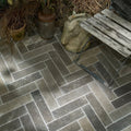 Dark gray herringbone patterned kimmeridge limestone tumbled and etched parquet stone tiles with textured finish