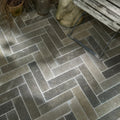 Dark gray herringbone patterned kimmeridge limestone tumbled and etched parquet floor tiles with stone-like texture