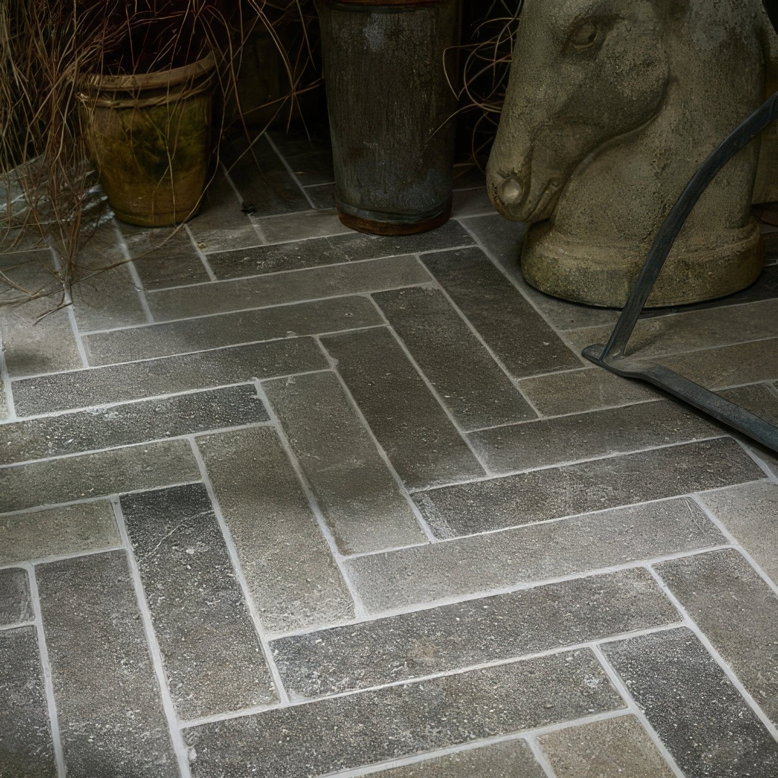 Dark gray kimmeridge limestone tumbled and etched parquet tiles arranged in a herringbone pattern