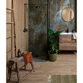 Komodo Porcelain Green teal marble-effect tiles with a wooden stool and orange towel