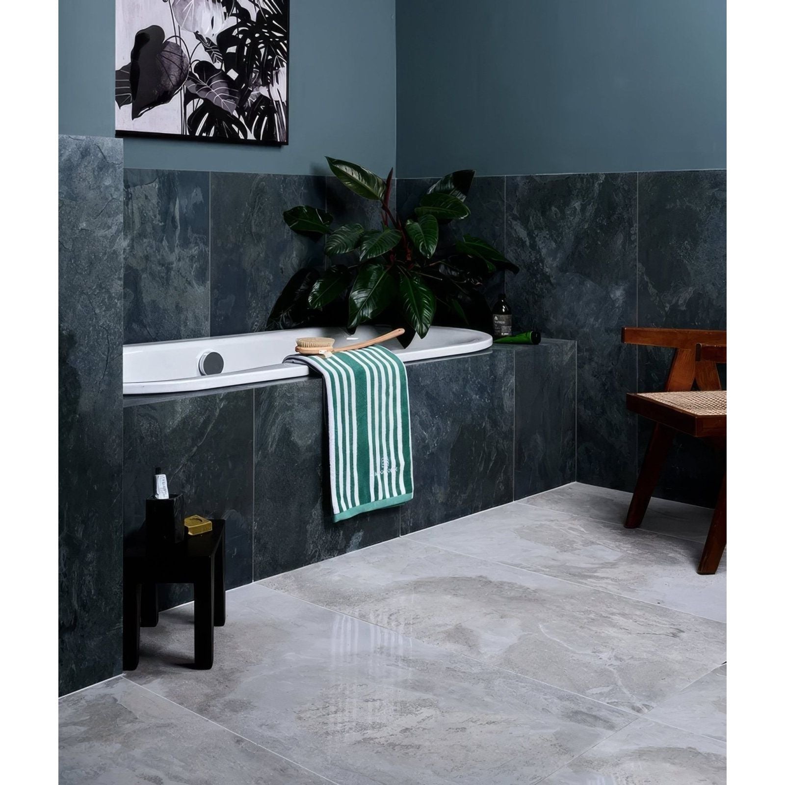 Komodo porcelain ocean bathtub with green and white striped towel draped over the edge of the modern tub