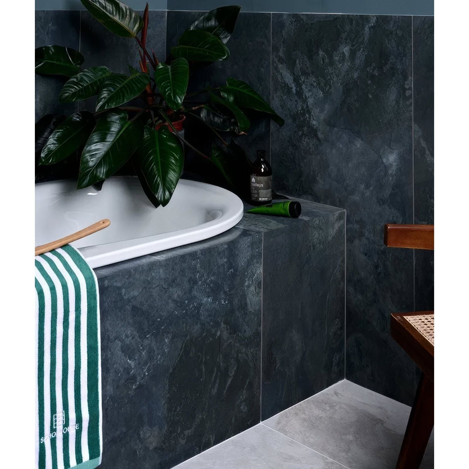Komodo porcelain ocean green and white striped towel hanging beside a white porcelain bathtub