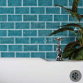 Chrome-finished cross-handle faucet with polished reflective surface in front of lagoon brick tile background