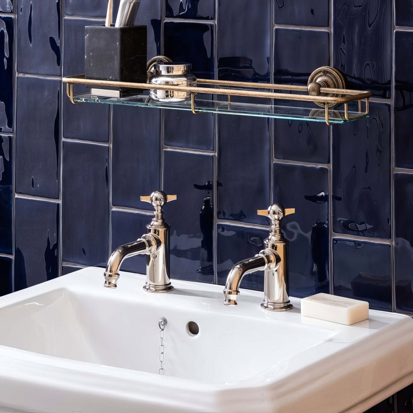 Polished chrome faucets with ornate cross handles atop white ceramic sink paired with lapis half tile wall tiles