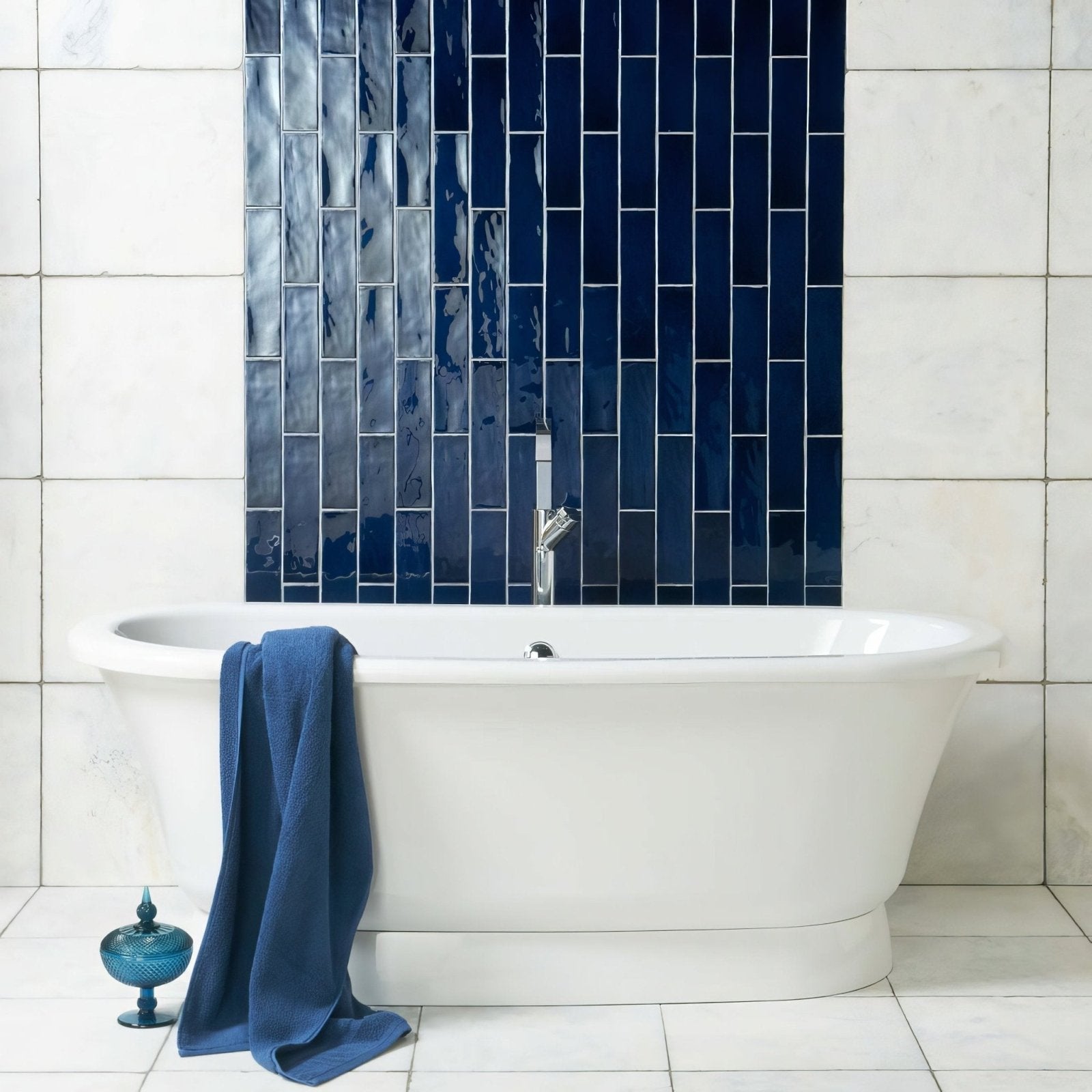 White freestanding bathtub with chrome faucet against navy blue lapis large brick tile wall background