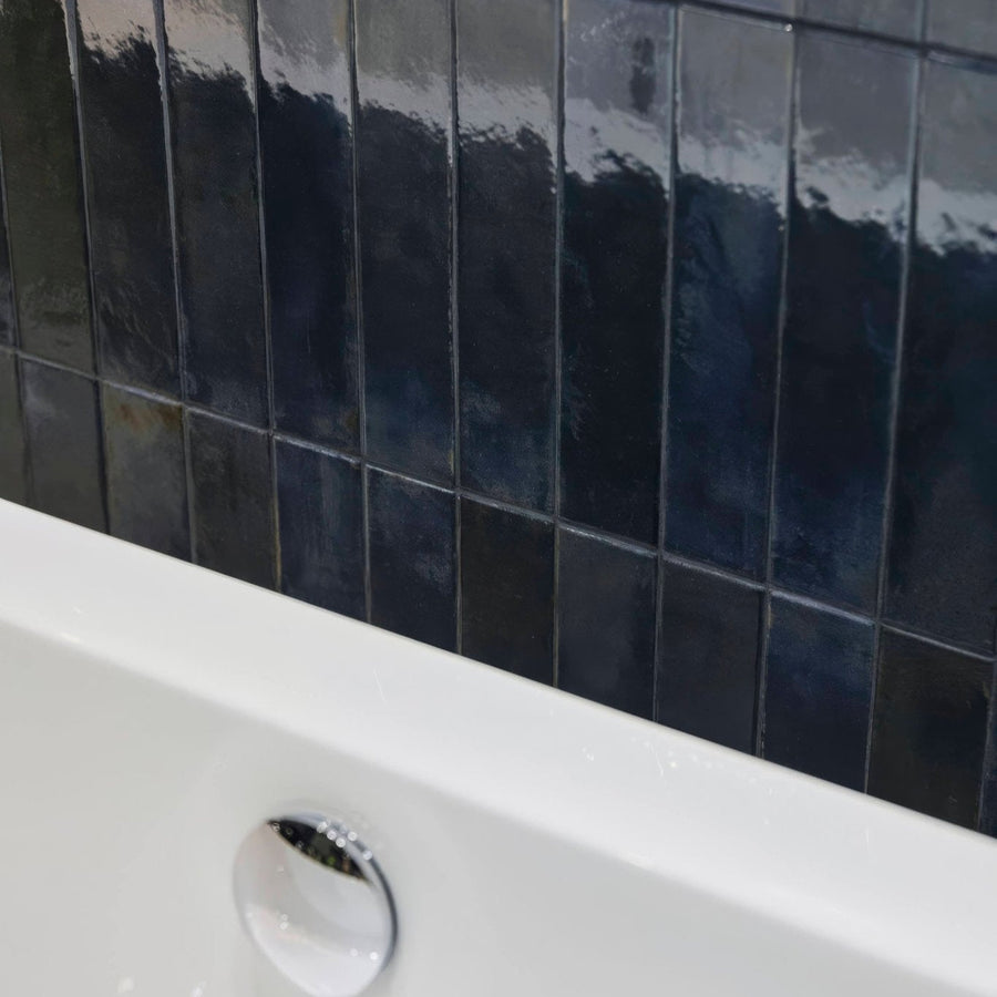 Dark blue glossy rectangular Lisbon blue cobalt shine tiles with subtle gradient and texture behind a white bathtub