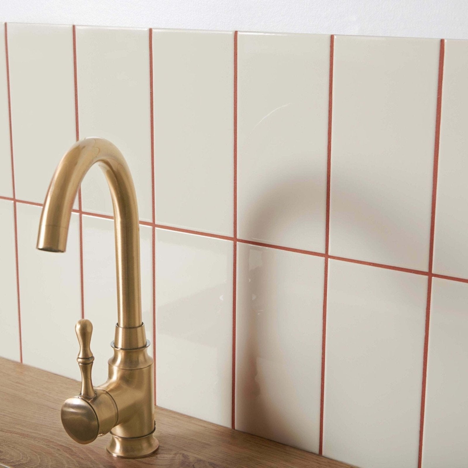 Brass-finished kitchen faucet with curved spout and ornate handle featured on liso bone gloss 100x200 product tile