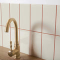 Brass-finished kitchen faucet with curved spout and ornate handle featured on liso bone gloss 100x200 product tile