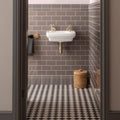 White ceramic london stone half tile wall-mounted sink with gold-toned faucets and visible plumbing