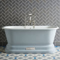 A light blue freestanding bathtub with classic design and chrome fixtures shown with london stone skirting tile
