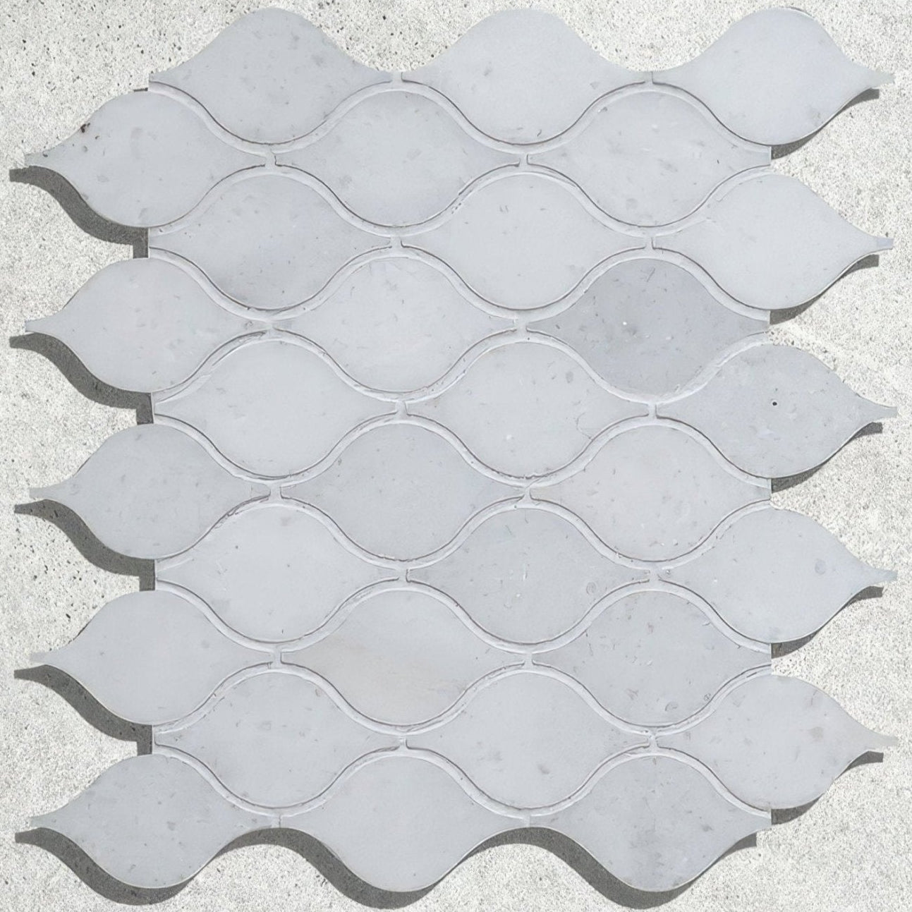 Long island marble teardrop mosaic tiles with light gray wavy-edged marble in a repeating pattern