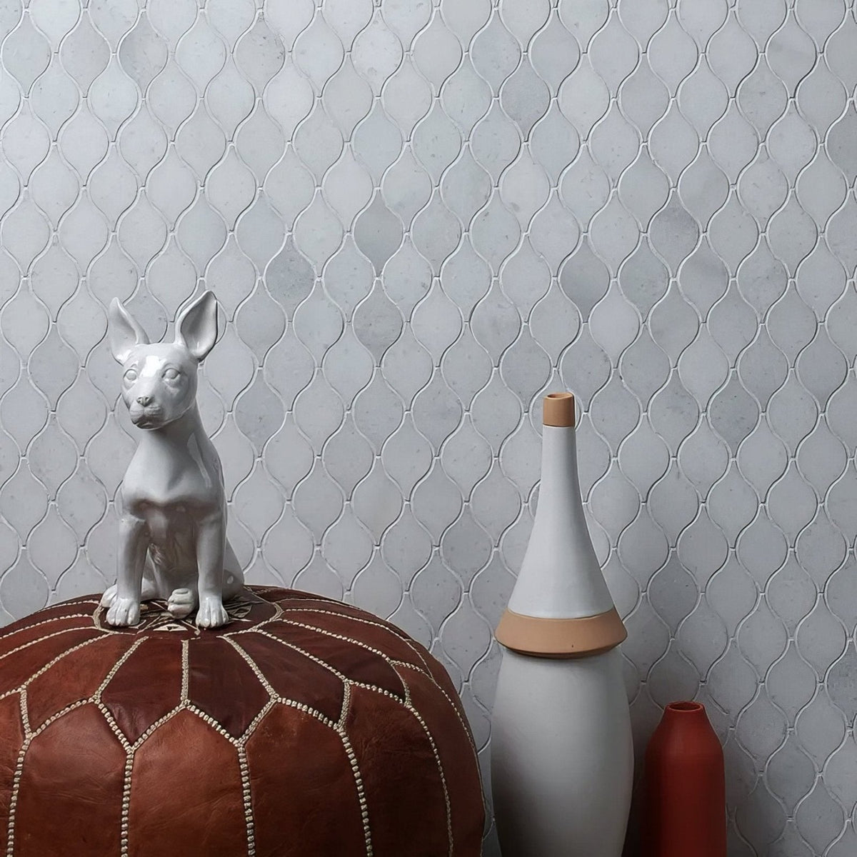 Long Island Marble Teardrop Mosaic light grey marble teardrop mosaic with a white ceramic dog figurine on a leather pouf