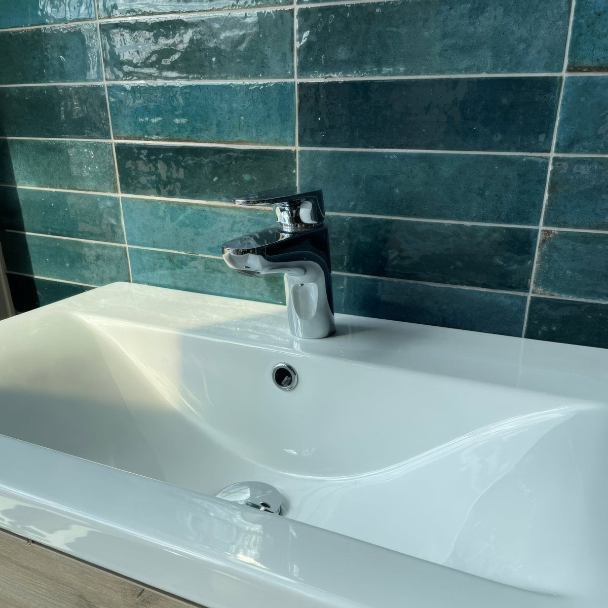 Luminous Lume Blue chrome-finished single-handle bathroom faucet mounted on white ceramic sink with teal tiles