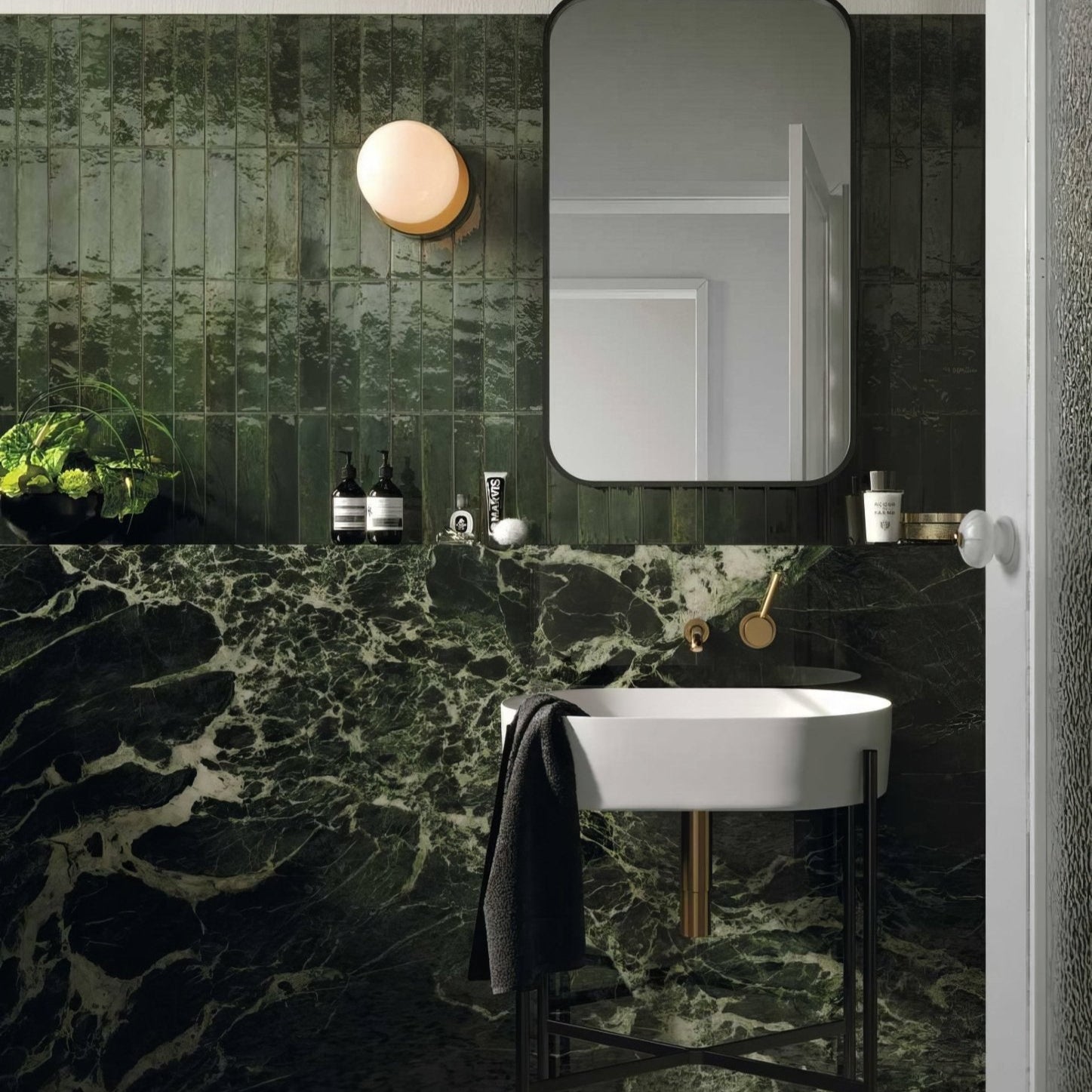 Luminous Lume Green white oval sink with minimalist black metal stand and gold faucet on dark green marble walls