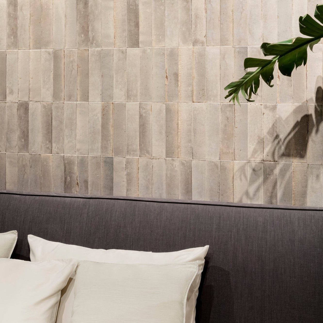 Gray textured rectangular wall tiles arranged in vertical rows from luminous lume greige collection