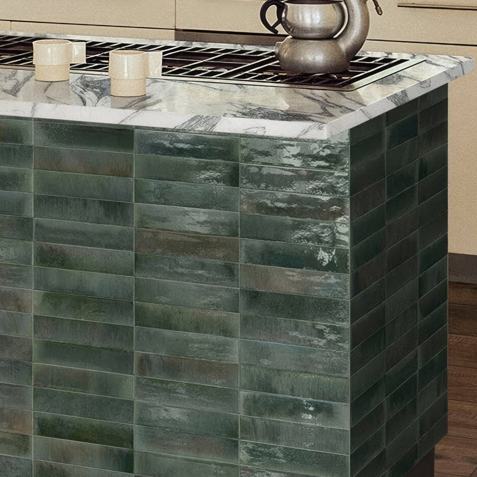 The kitchen island features a sleek dark green ceramic tile facade with a marbled texture and glossy finish in Luminous Lume Verde Forest