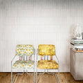 Two luminous lume white vintage-style chairs with chrome frames and bold yellow green cream floral upholstery