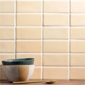 Stacked maize half tile ceramic bowls with matte dark green rim and two-toned beige and muted gold body beside golden spoon