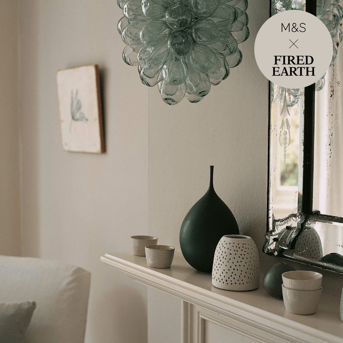 A sleek matte dark green ceramic vase with a long slender neck and rounded body from malm on a mantelpiece