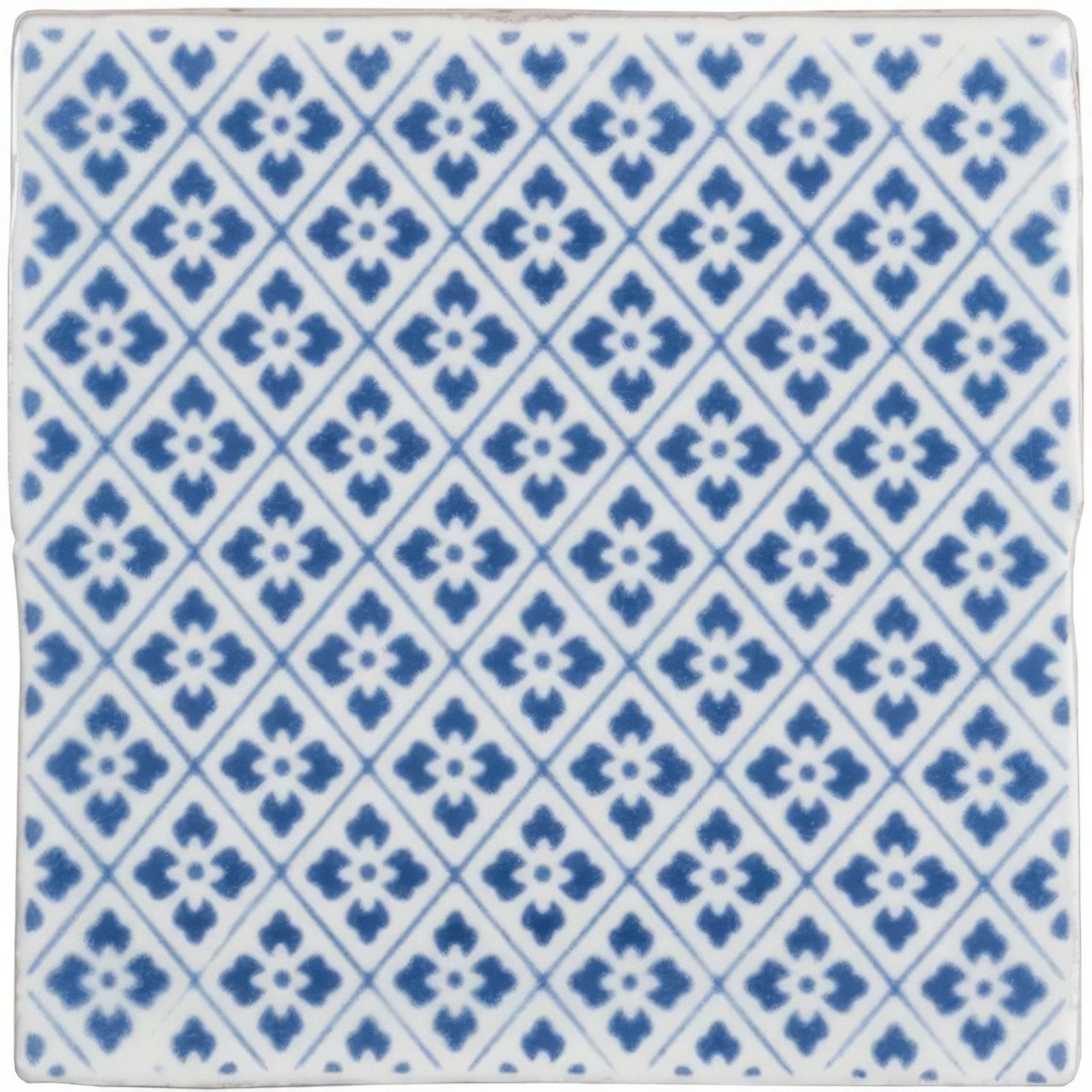 White ceramic tile from Manoir Provence on Papyrus with repeating blue diamond pattern and stylized four-petal flowers