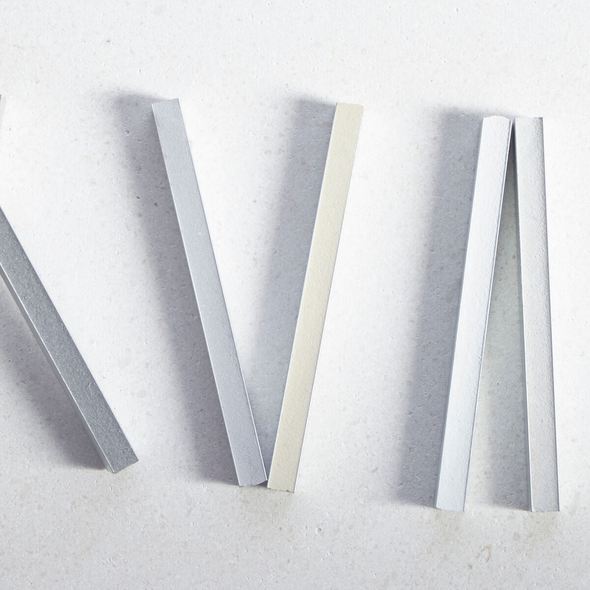 Silver and cream-colored metal strips for decorative or structural use shown with Mapei Ultracolour Plus grouts packaging