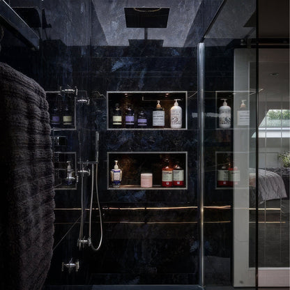 Modern shower with dark tiles in Marble Ocean Rock 60 x 120cm and glass walls displaying bottles.