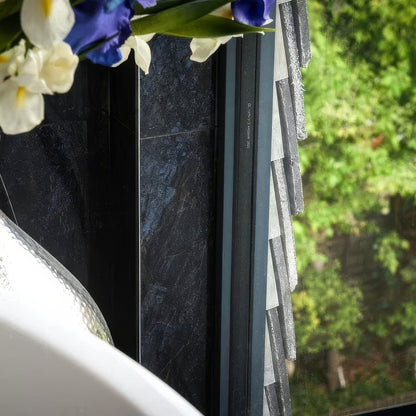 Vase with flowers next to a window with a view of trees