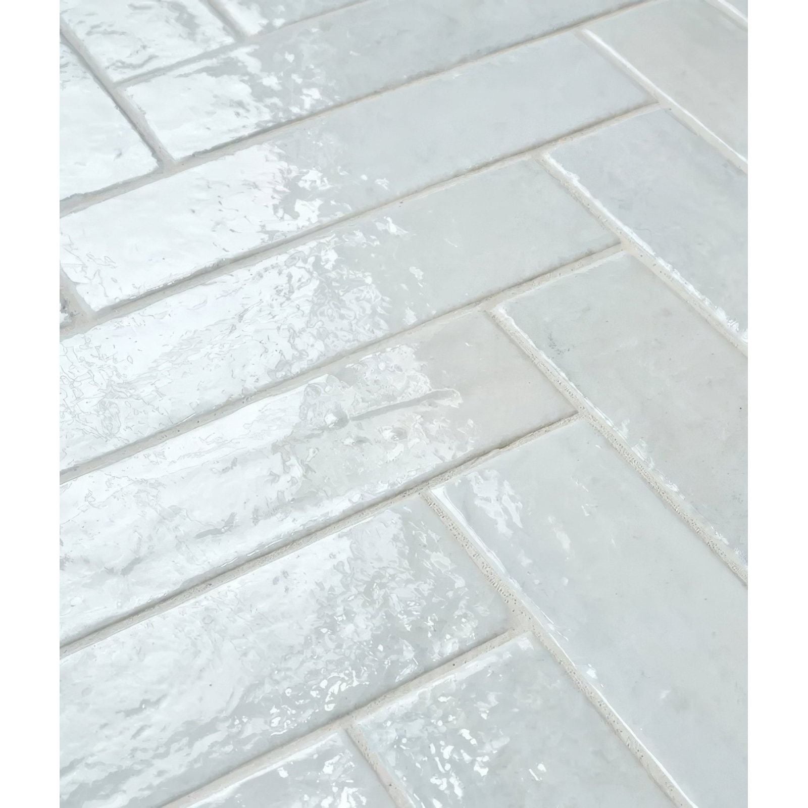 White glossy rectangular porcelain tiles in herringbone pattern with subtle texture and faint veining marlborough cotton white gloss