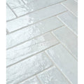 White glossy rectangular porcelain tiles in herringbone pattern with subtle texture and faint veining marlborough cotton white gloss