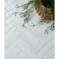 White rectangular ceramic tiles in a herringbone pattern from marlborough porcelain parquet cotton white gloss collection