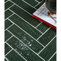 Dark green marlborough porcelain parquet tiles with textured herringbone pattern and white grout in gloss finish