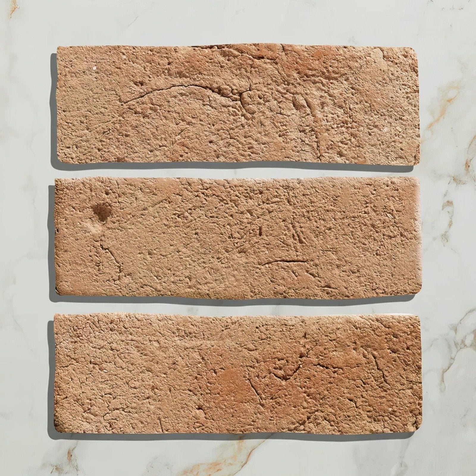 Three terracotta-colored marlborough bejmat ceramic tiles with rough textured surfaces and natural imperfections