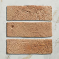 Three terracotta-colored marlborough bejmat ceramic tiles with rough textured surfaces and natural imperfections