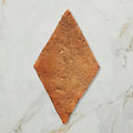 A rustic terracotta marlborough terracotta diamond tile with a rough textured surface and diamond shape