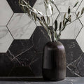 Marmi Nero Honed Hexagon Mosaic dark hexagonal marble mosaic with a black ribbed vase of olive branches