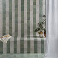 Green and white striped ceramic tiles from maroc ceramic mint forming a vertical pattern on a bathroom wall