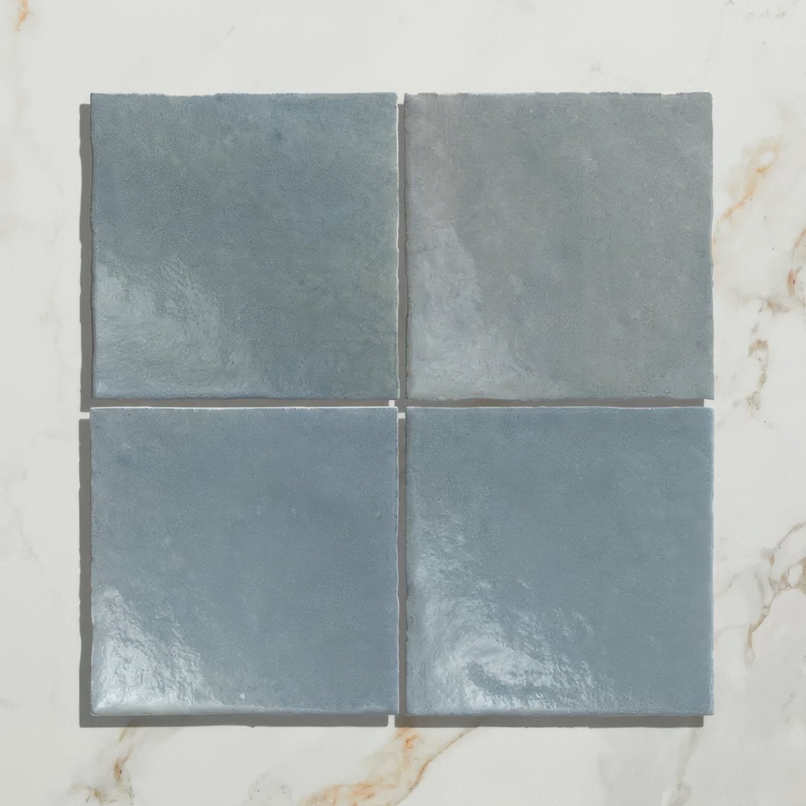 Four square matte-finished slate gray ceramic tiles from maroc ceramic powder blue collection arranged in a grid