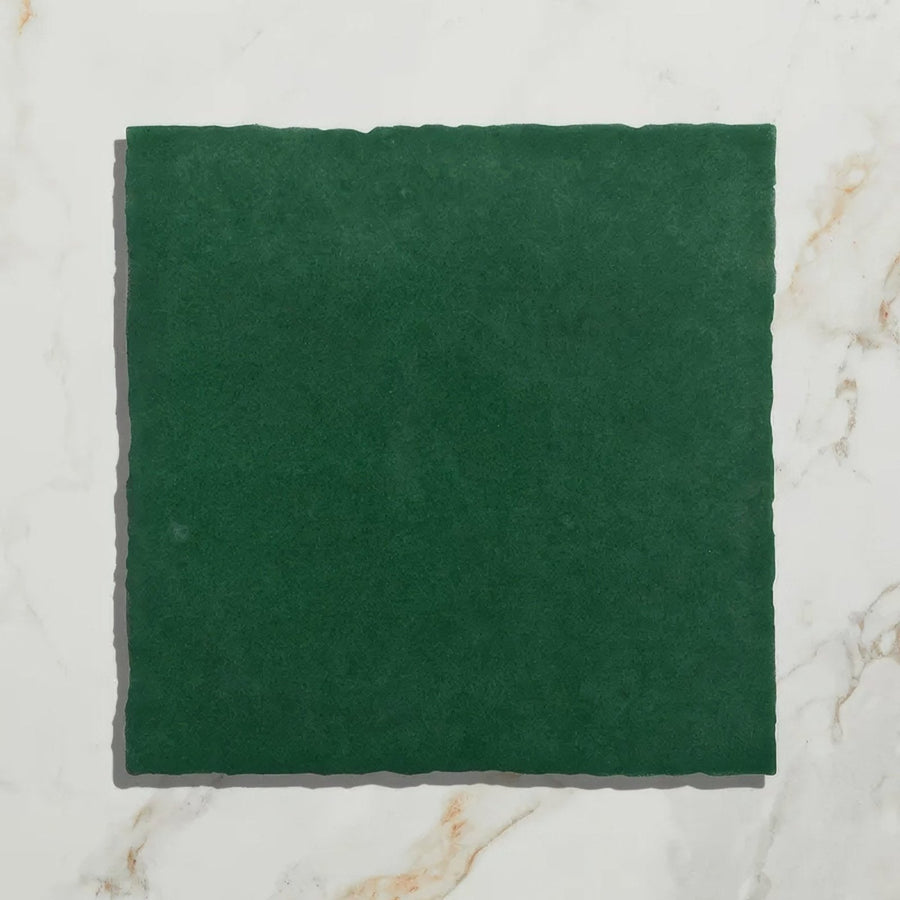 A square deep green maroc ceramic teal stone tile with textured uneven surface and softly irregular edges