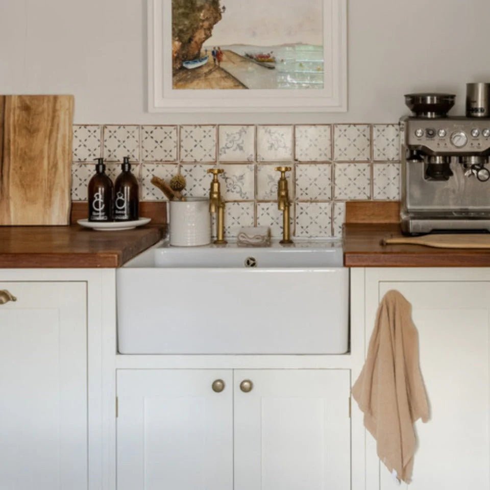 White farmhouse sink with brass faucets set against patterned terracotta Marrakech El Hara tile backsplash