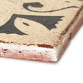 A rustic beige ceramic Marrakech hammam patterned terracotta tile with distressed edges and a black fish design