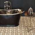 Black freestanding bathtub with polished chrome rim and vintage faucet on patterned terracotta tile floor