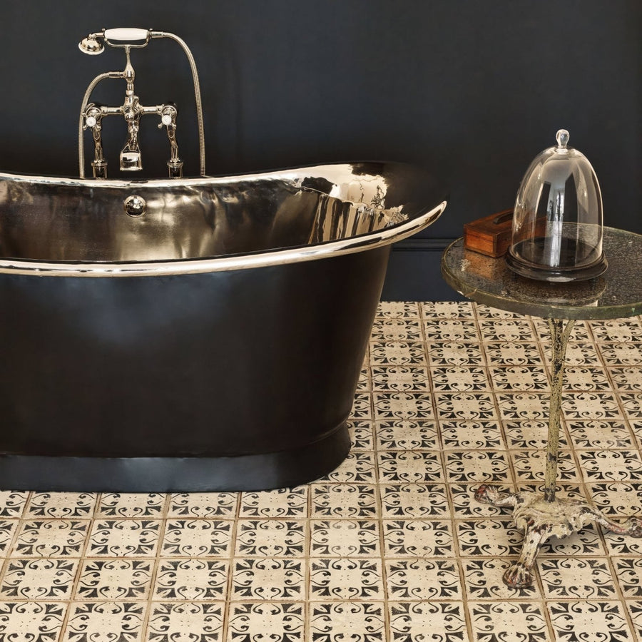 Black freestanding bathtub with polished chrome rim and vintage faucet on patterned terracotta tile floor