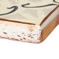 Cream-colored ceramic marrakech mabrouka terracotta tile with rustic textured edges and black decorative swirls