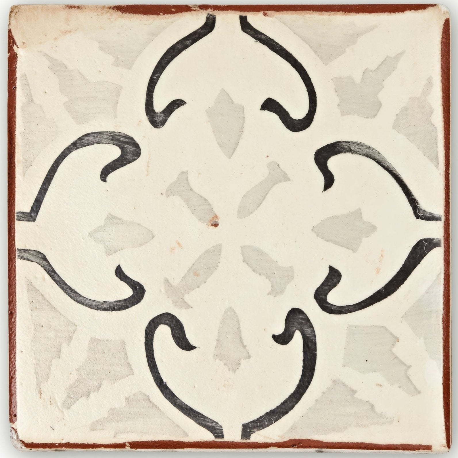 Cream-colored ceramic Marrakech Mabrouka patterned terracotta tile with black floral design and rustic reddish-brown border