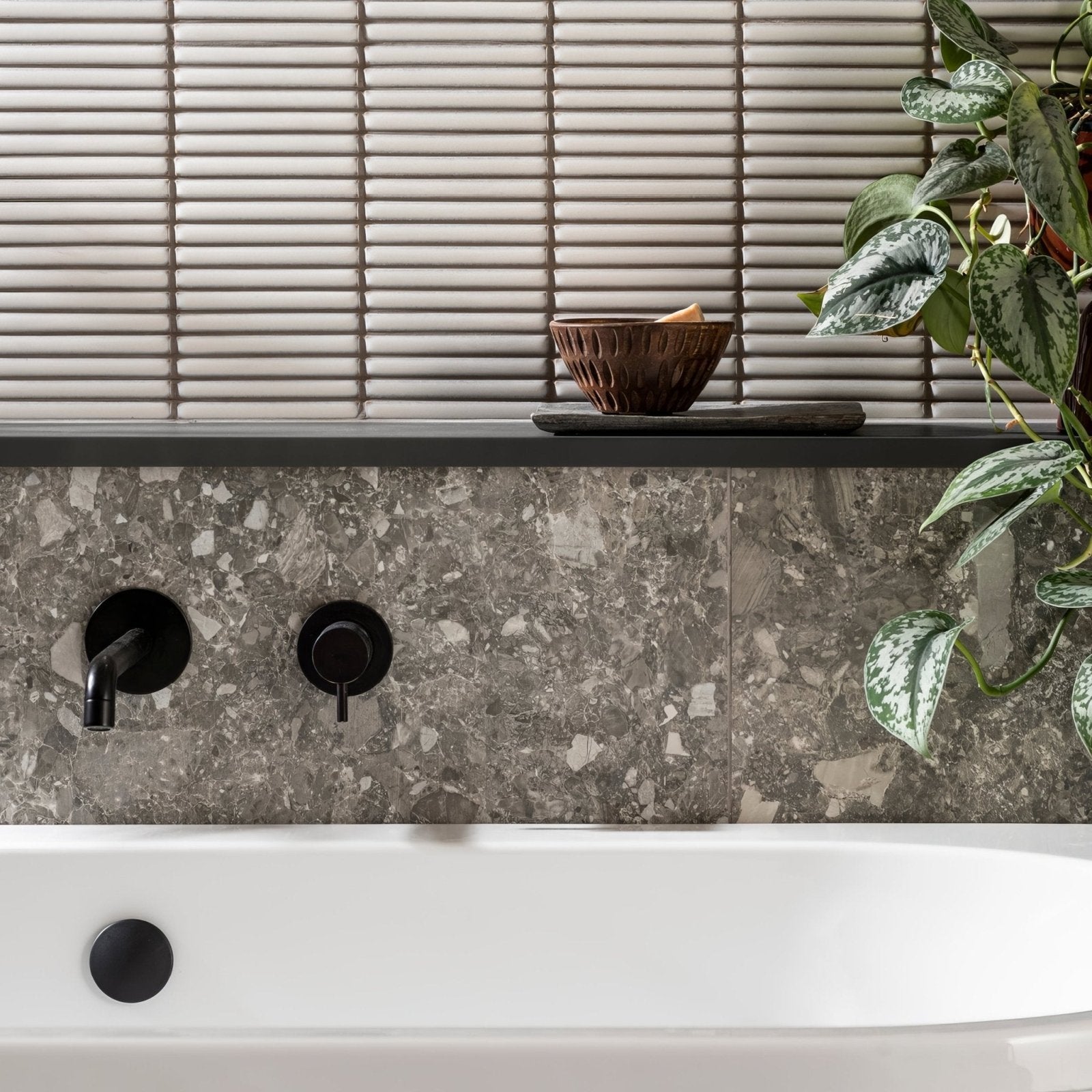 Matchstick Ice white glass mosaic with a black wall-mounted bath tap
